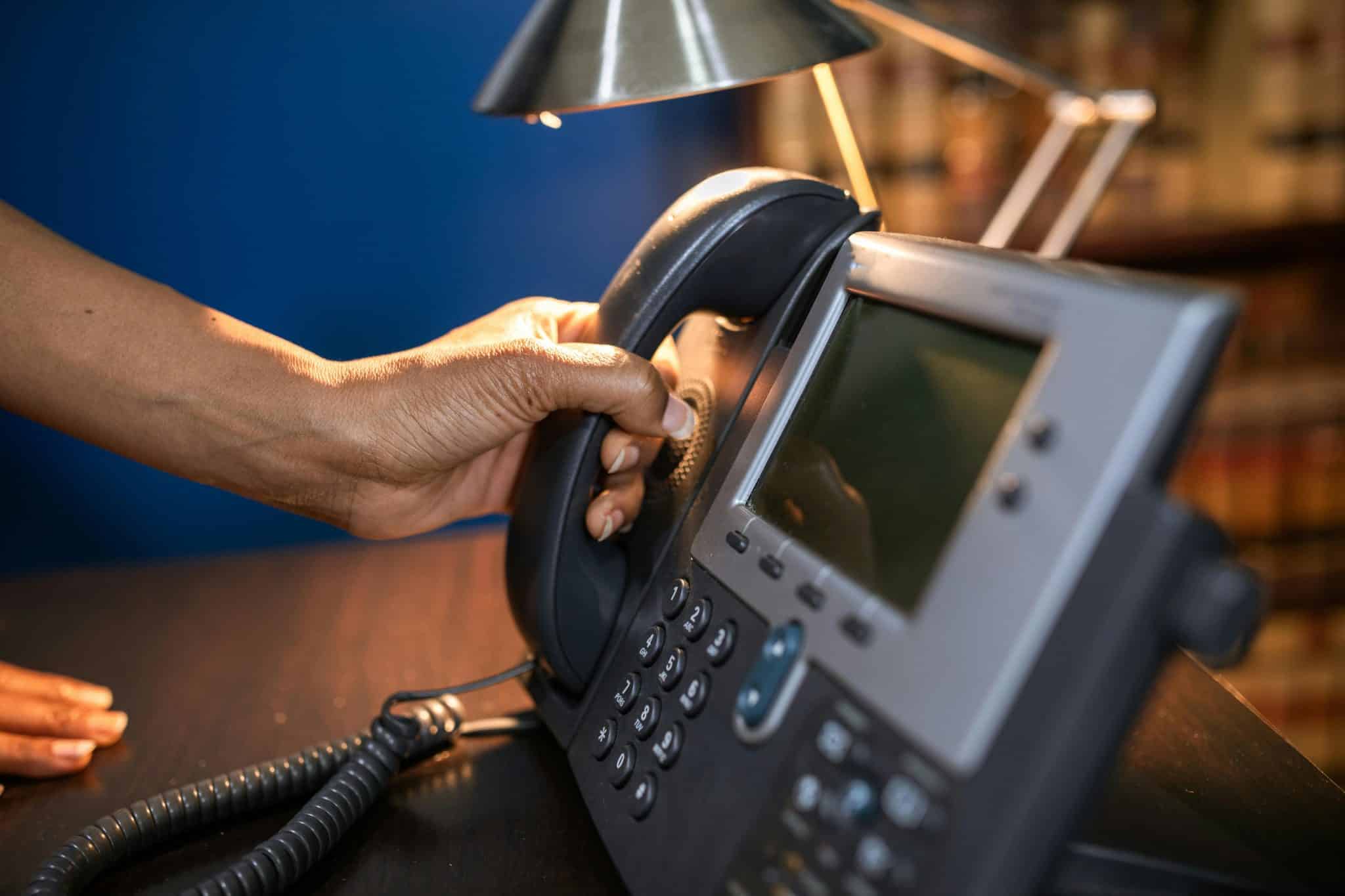 Close-up of a hand lifting the receiver of a business phone, representing ICS Networking’s business phone and hosted communication solutions in Terre Haute, Indiana.